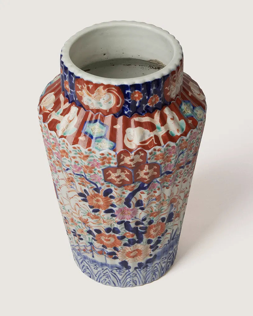 High-angle overhead view of an antique Imari style ribbed porcelain vase, showing the open rim and the dense polychrome floral patterns cascading down the body.