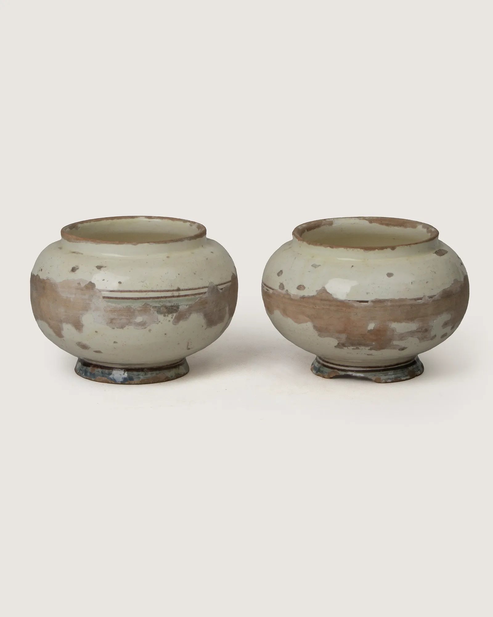 Pair of early 1900s antique terracotta cachepots from Central Italy with a beautifully distressed white glazed patina.