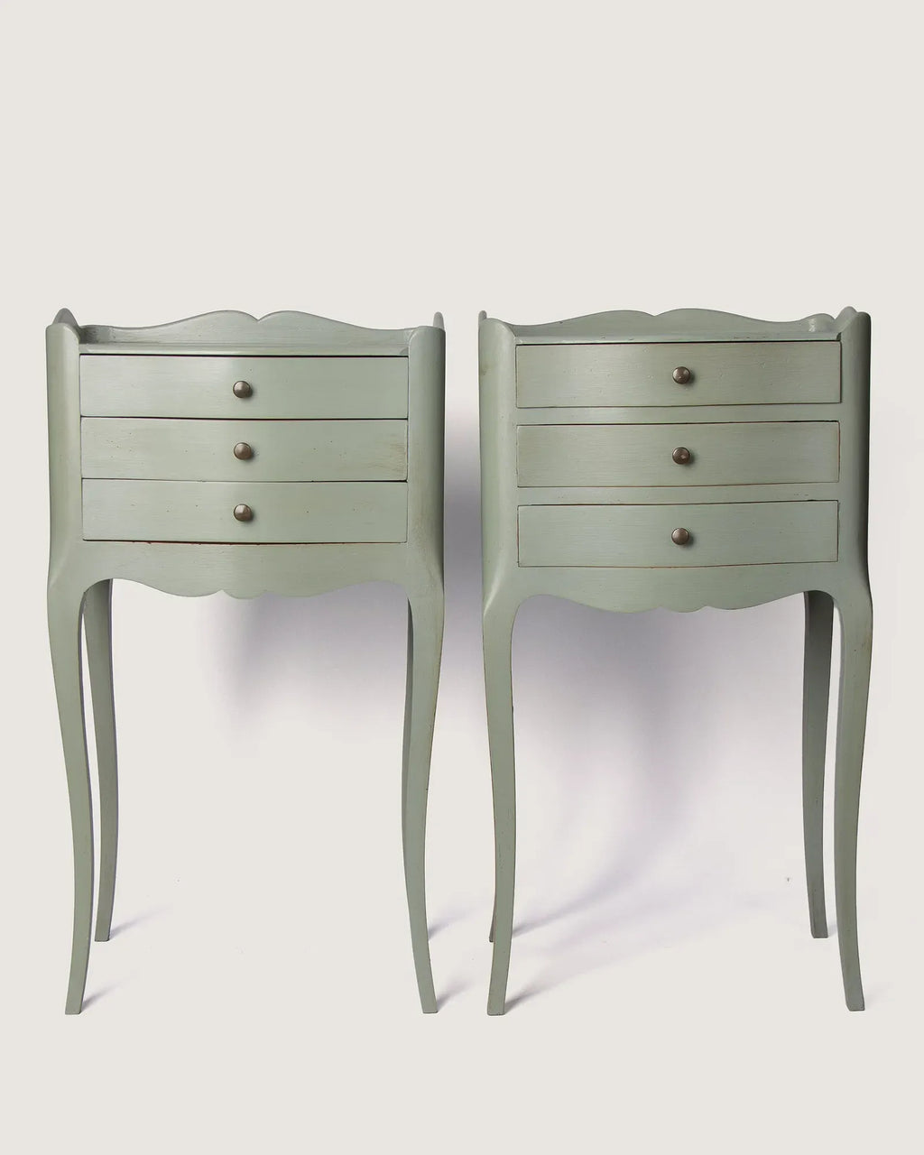 Full front view of the two unique antique French nightstands showing the symmetrical three-drawer design and slightly asymmetric undulating lines.