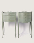 Full front view of the two unique antique French nightstands showing the symmetrical three-drawer design and slightly asymmetric undulating lines.